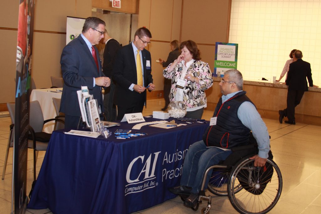 CAI talks with attendees at their exhibitor table at the Disability Inclusion Opportunity Summit 