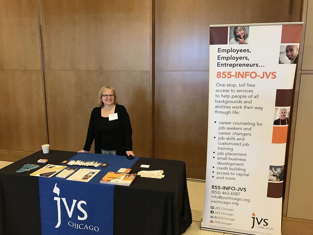 Nanette Cohen stands at the JVS Chicago exhibitor table at the Disability Inclusoin Opportunity Summit