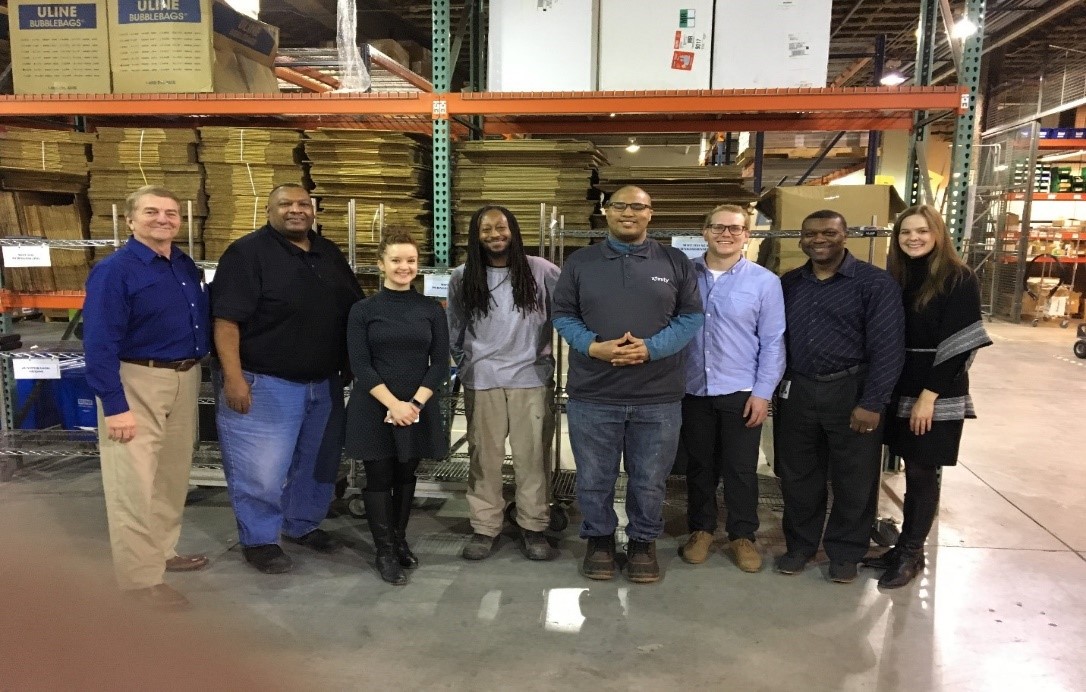 Group photo of P.A.C.E. program participants posing in a wharehouse.