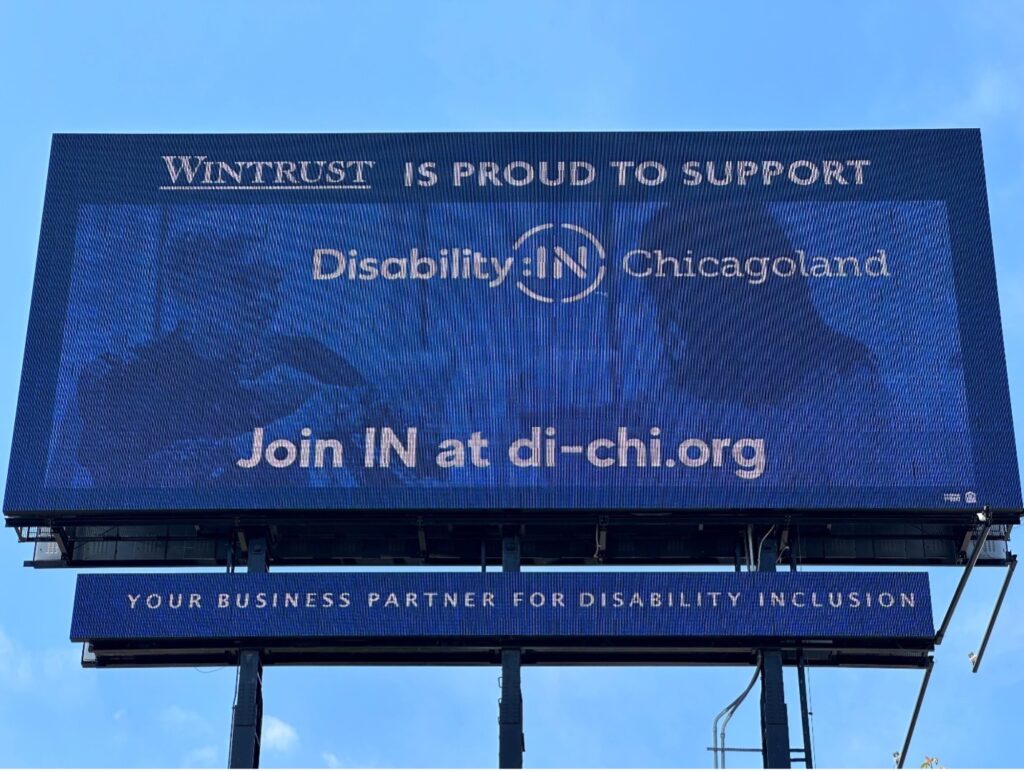 Billboard in blue with a background photo of two women in an office signing and includes text Wintrust is proud to support DisabilityIN Chicagoland your business partner for disability inclusion.